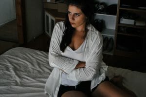 woman sitting and holding her stomach, her digestion symptoms may be from SIBO